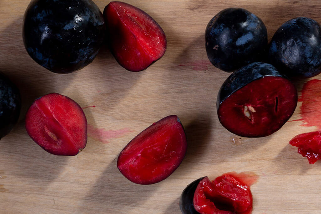 Brookfarm native ingredients, close up of Davidson Plums chopped on a board